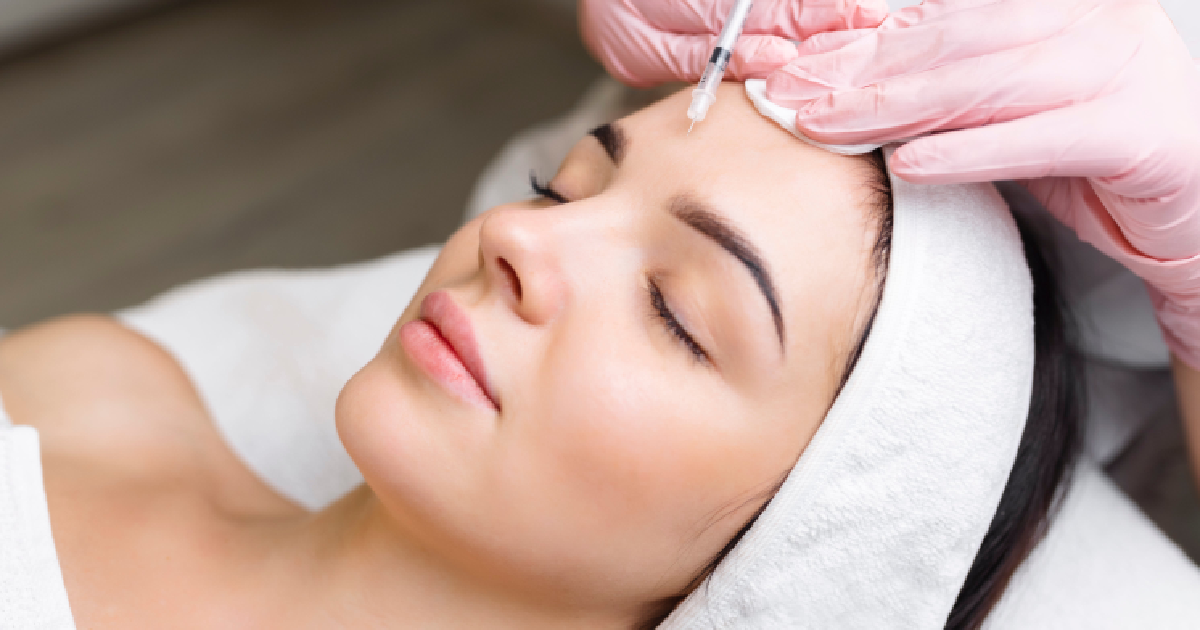A woman receiving a forehead injection, likely Botox, in a clinical in Sandy, UT