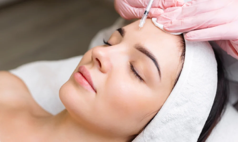 A woman receiving a forehead injection, likely Botox, in a clinical in Sandy, UT